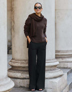 Model steht im Zora Espresso Pullover aus Alpaka-Mischung mit einer weiten schwarzen Hose.