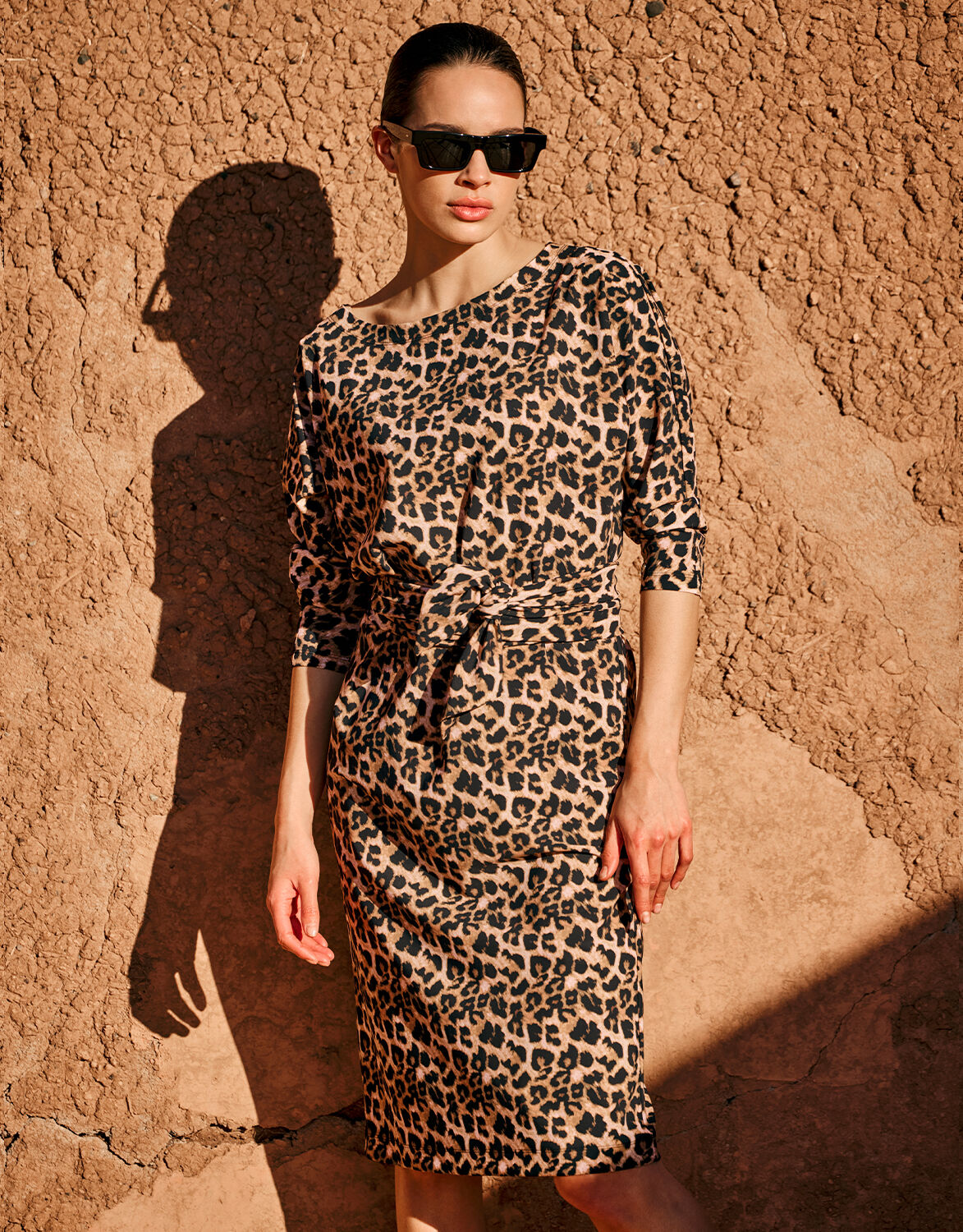 Model standing in the Caroline Animal dress in jersey lycra with a leopard print and tie waist.