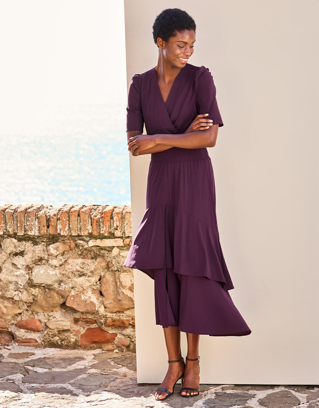 Model standing in the Lea Deep Aubergine dress in jersey lycra with a wrap front.