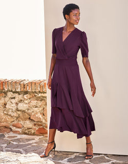 Model standing in the Lea Deep Aubergine dress in jersey lycra with a tiered ruffled hem.