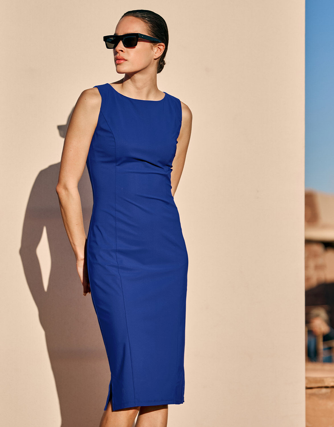 Model standing in the Gloria Marine Blue dress in jersey lycra with sunglasses.