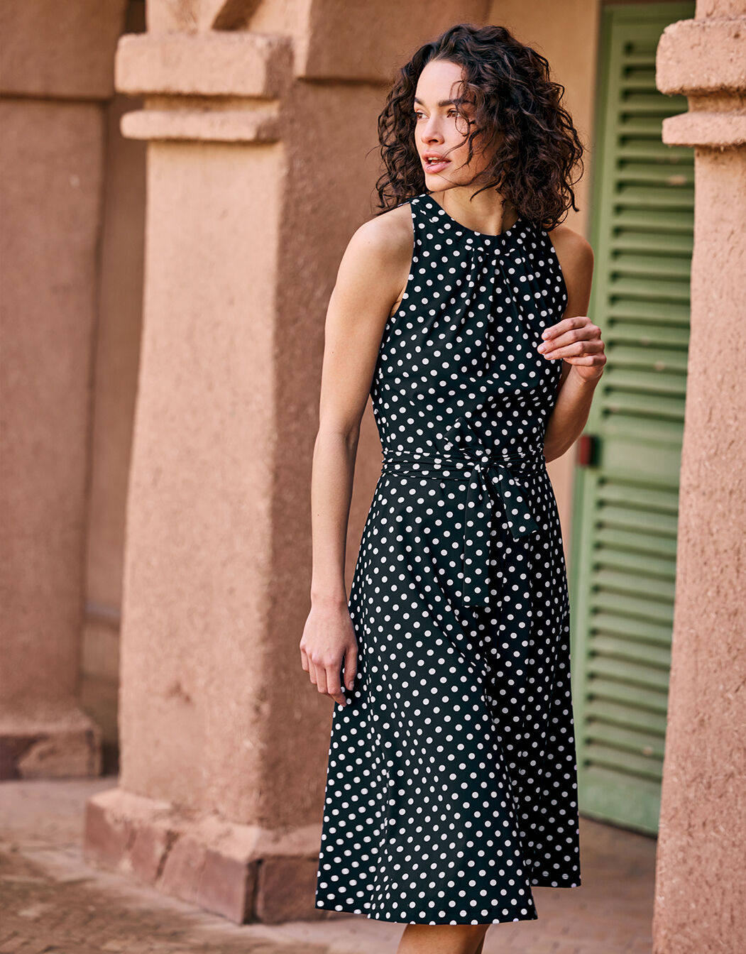 Model standing in the Juno Ivory small dot dress in jersey lycra with a polka dot print.