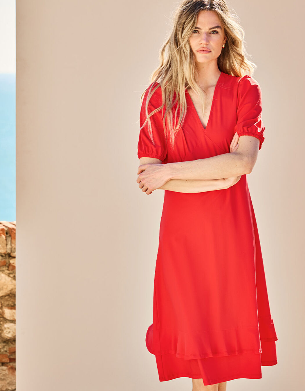 Model standing in the Kaya Hibiscus dress in jersey lycra with a V-neck and puff sleeves.