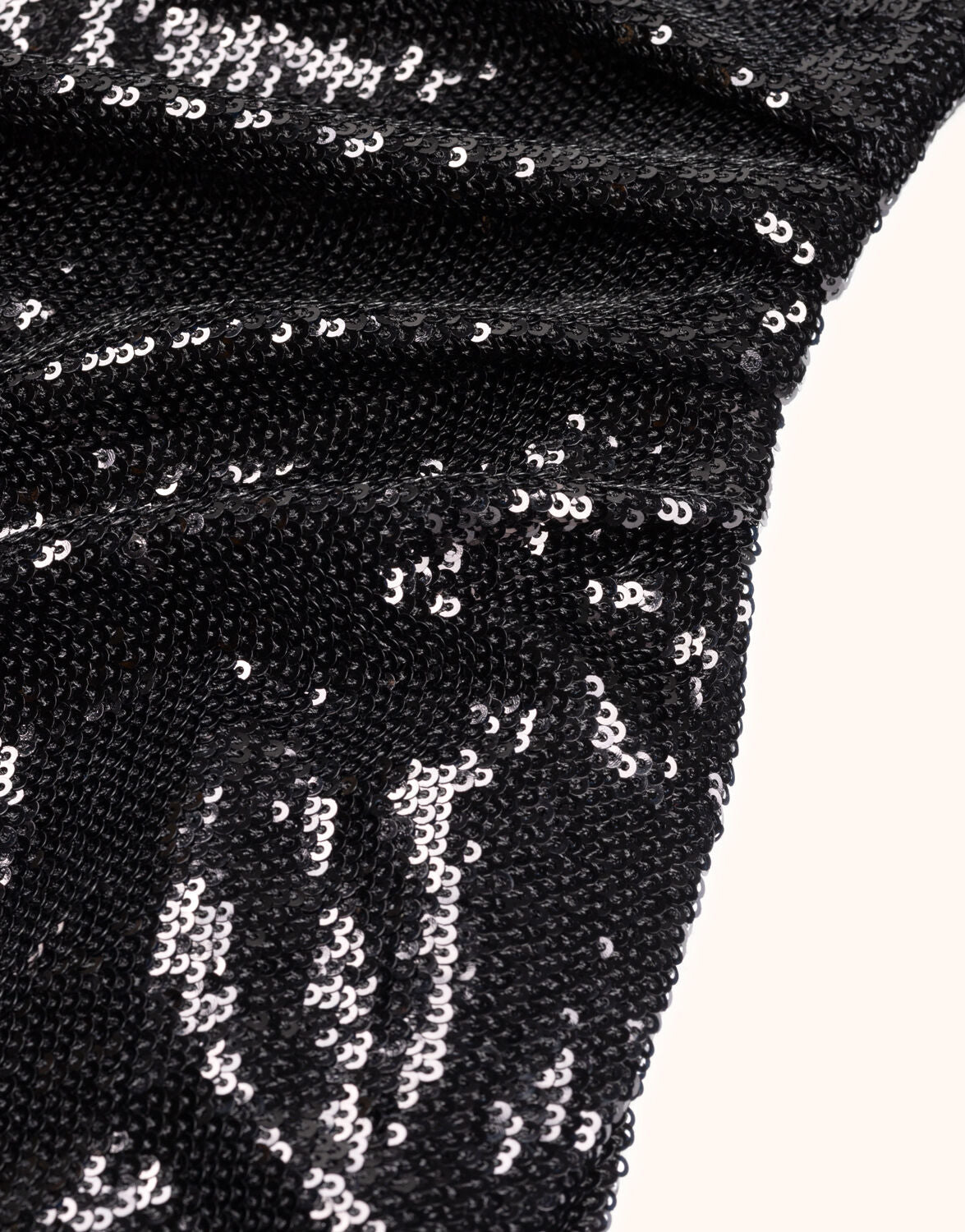 Black sequin fabric with a glossy texture and flowing pleats, ideal for evening wear or festive outfits.