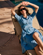 Woman dressed in a blue denim dress, with sunglasses, enjoying the summer day.