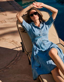 Woman dressed in a blue denim dress, with sunglasses, enjoying the summer day.