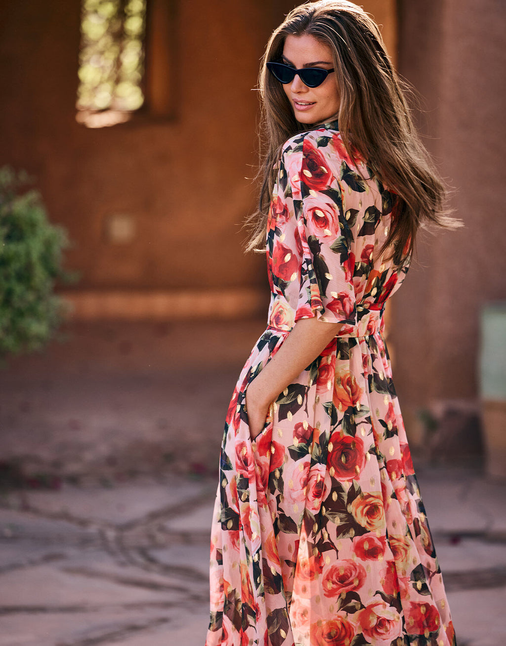 Woman in a colorful floral dress with a pink and red rose print.