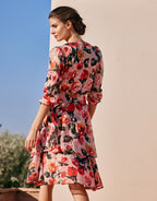 Floral dress with pink and red rose print, woman with updo. Garden party style in a summery atmosphere.
