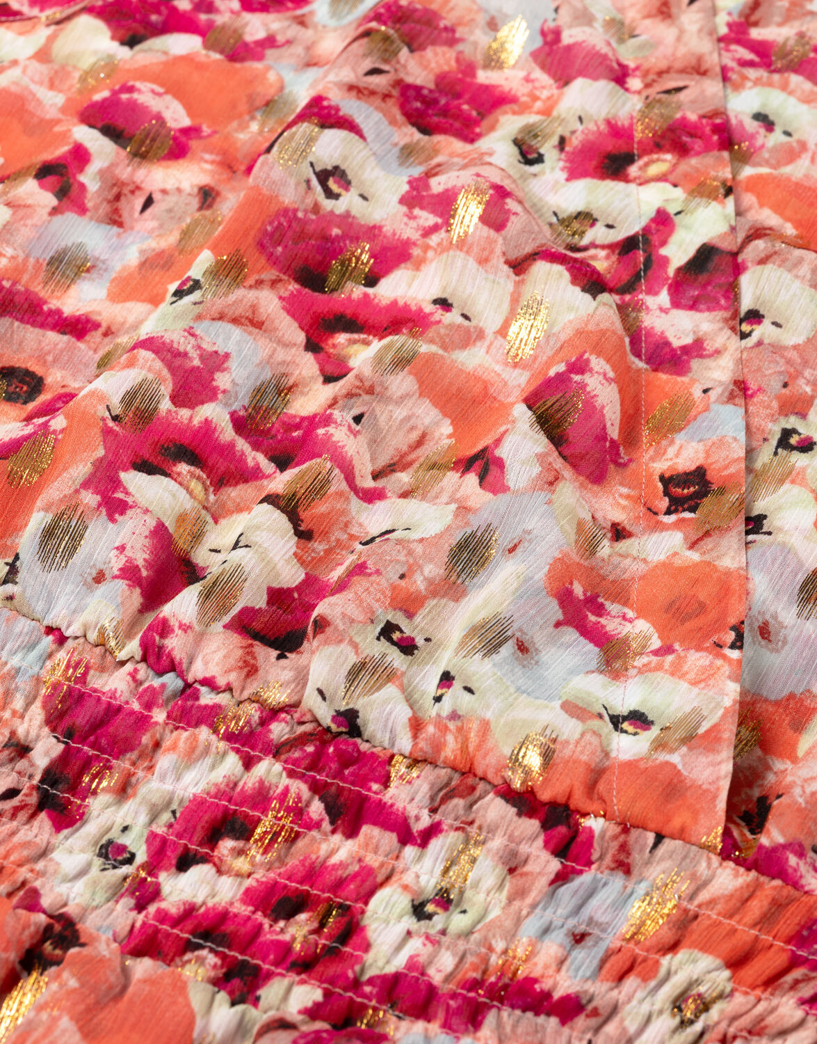 Bright pink and orange floral fabric with gold accents, close-up of the colorful and vibrant floral print on cotton.