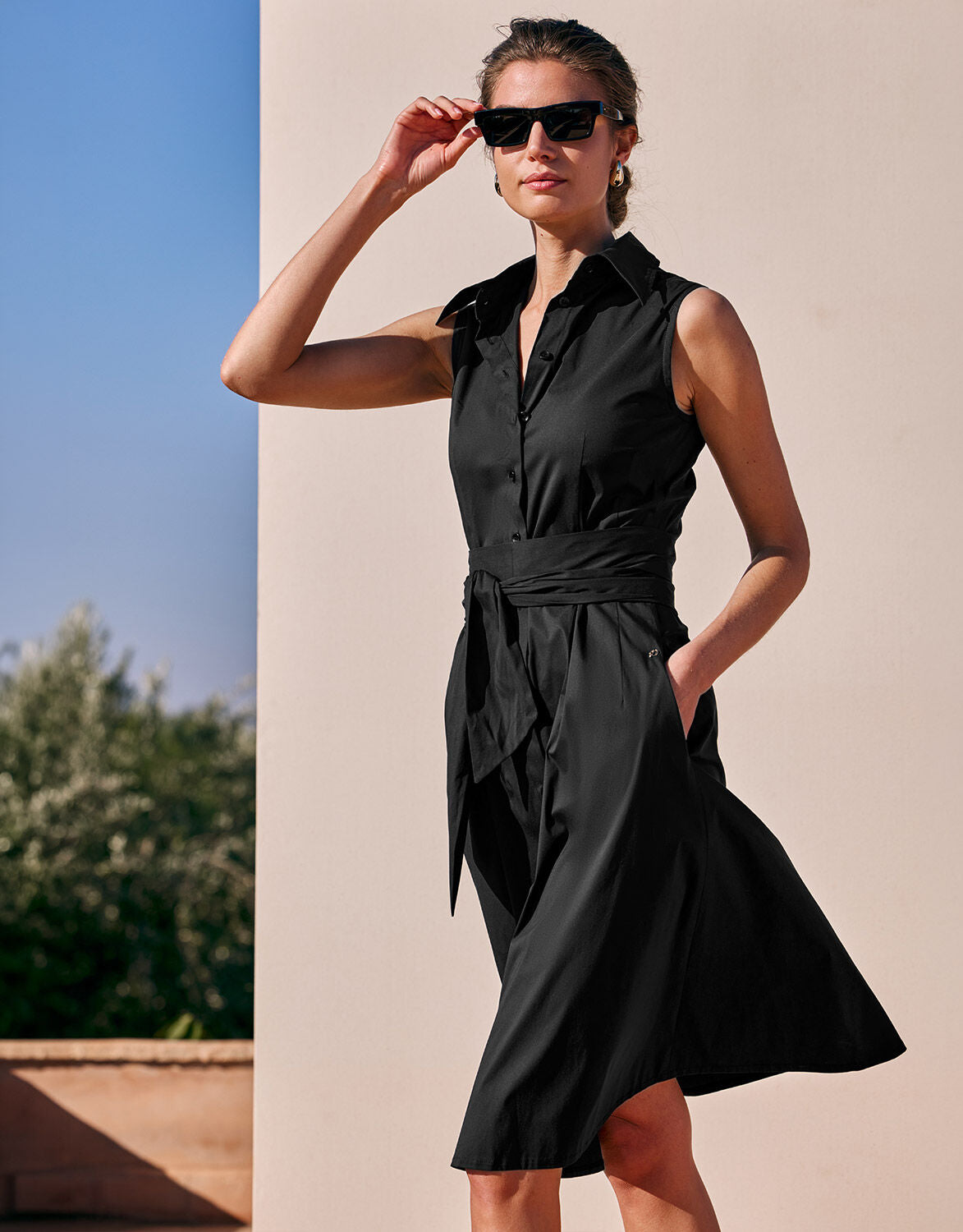 Model standing in the Leonie Black dress in cotton stretch poplin with a tie belt.
