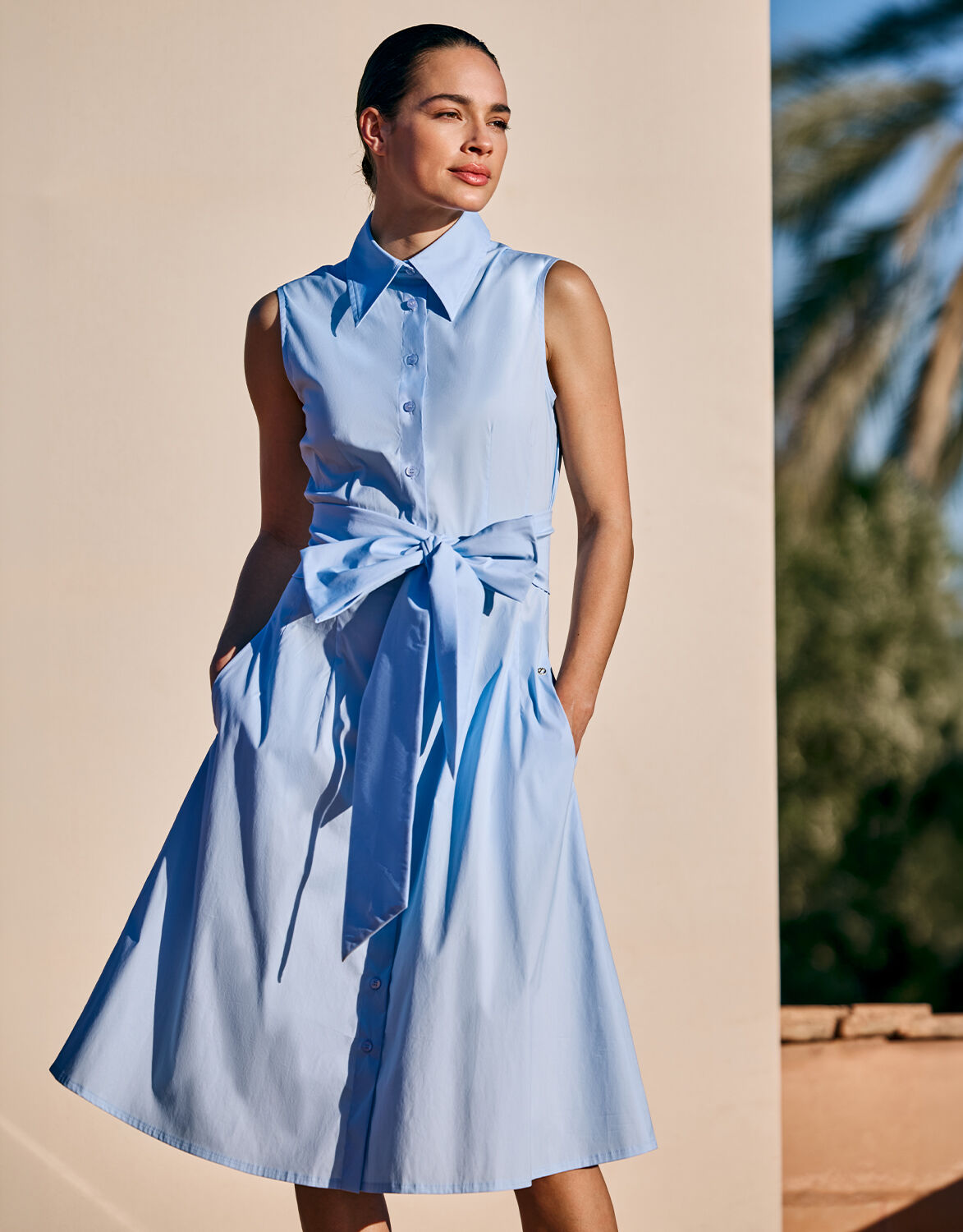 Model standing in the Leonie Light Blue dress in cotton stretch poplin with a tie belt.