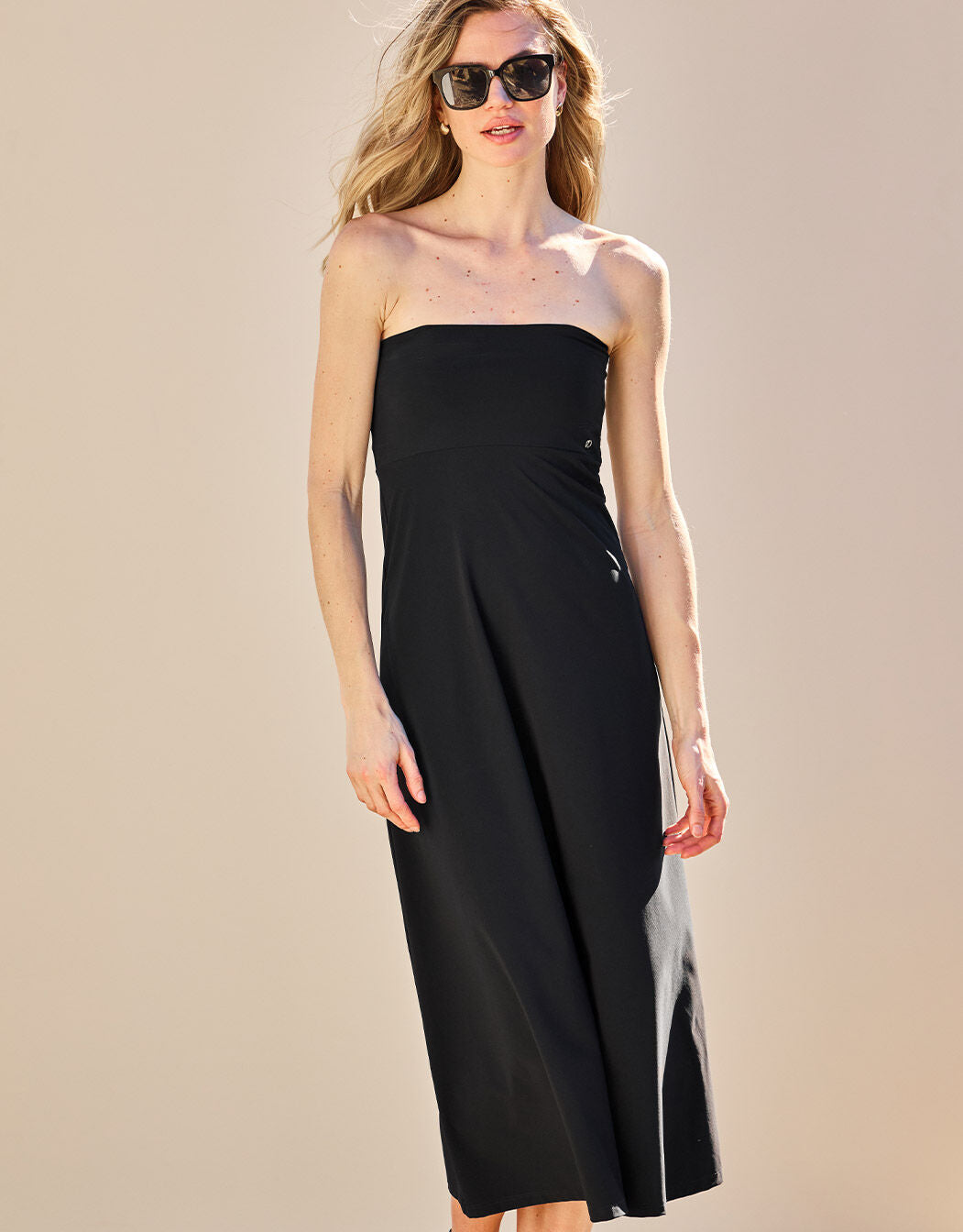 Model standing in the Tropez Black dress in jersey lycra, a long strapless style.