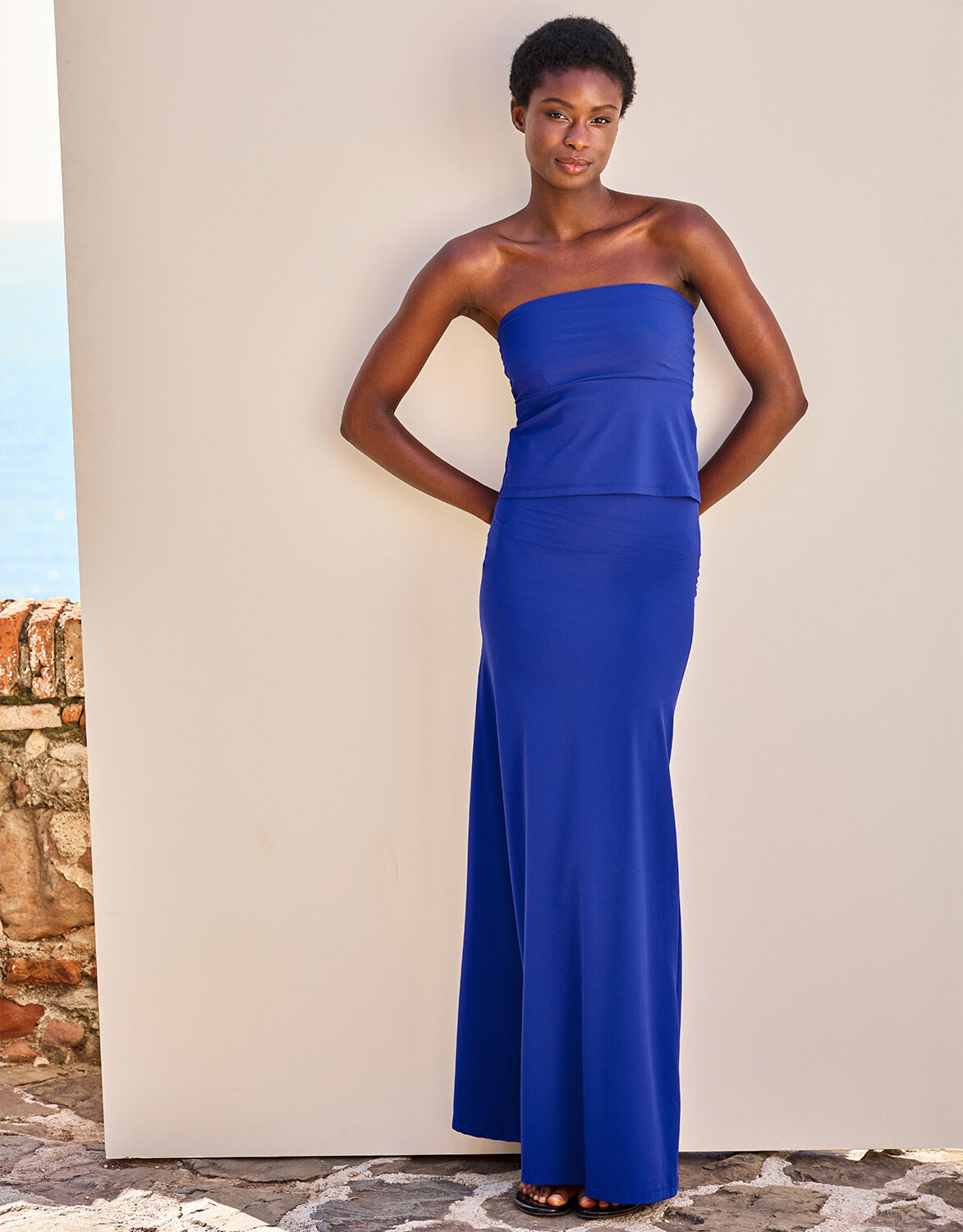 Model standing in the Tropez Marine Blue dress in jersey lycra, a long strapless style.