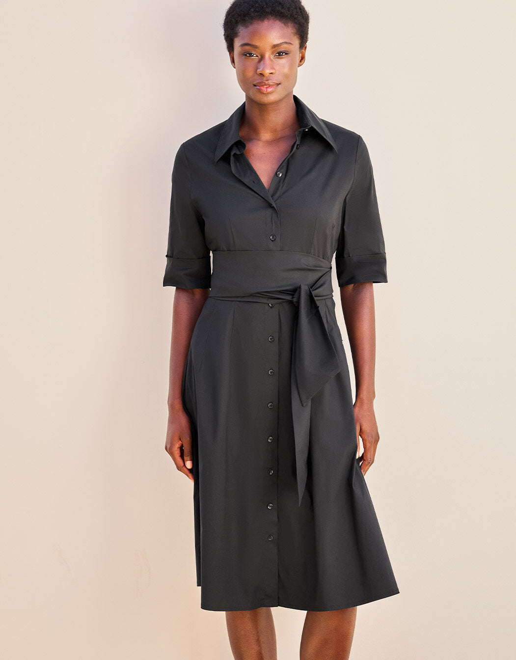 Model standing in the Vera Black dress in cotton stretch poplin with a tie belt.