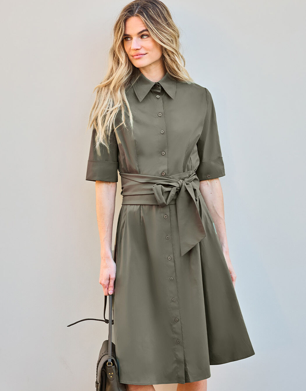 Model standing in the Vera Olive dress in cotton stretch poplin with a tie belt.