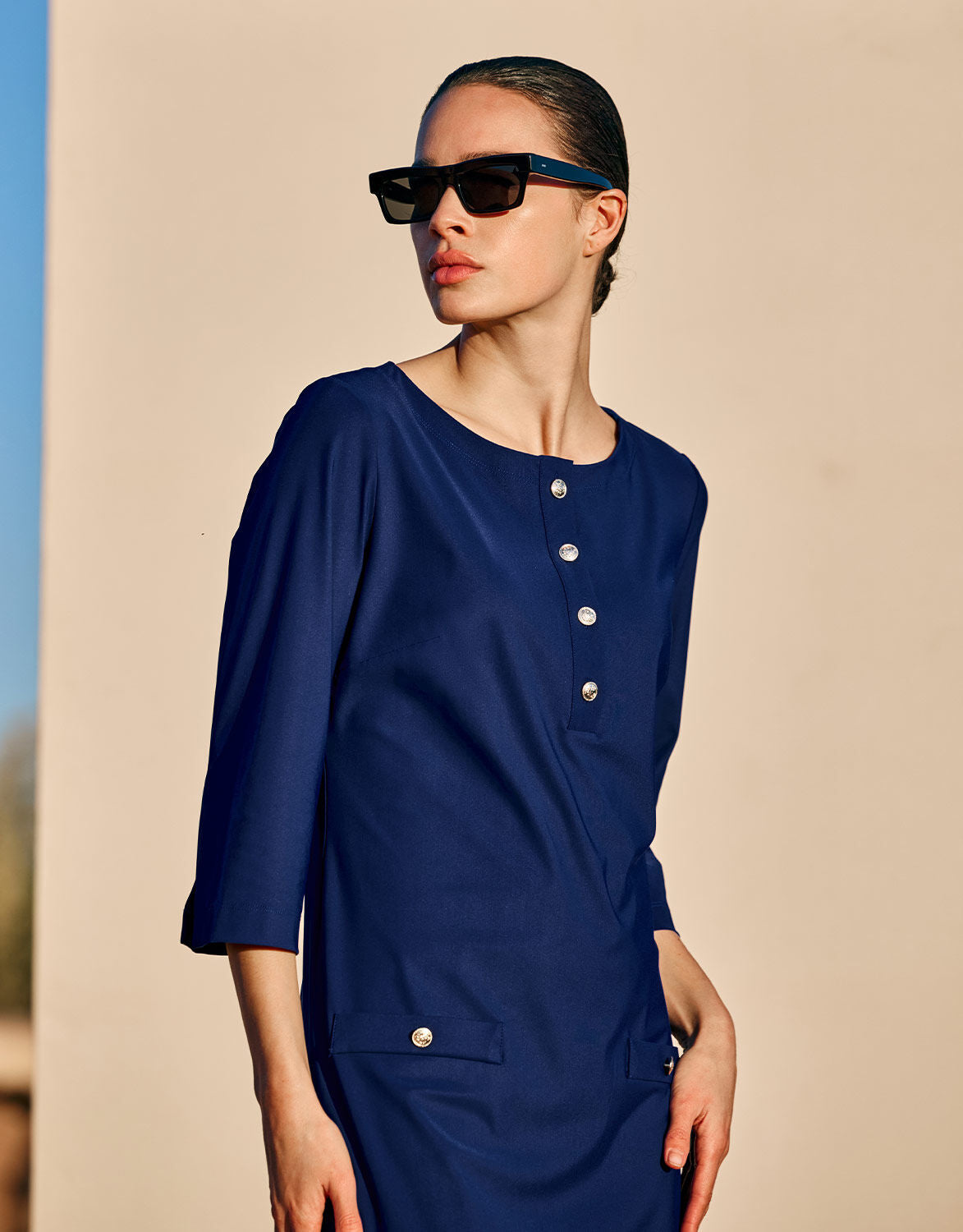 Model standing in the Pearl Sapphire Blue dress in jersey lycra with a button placket.