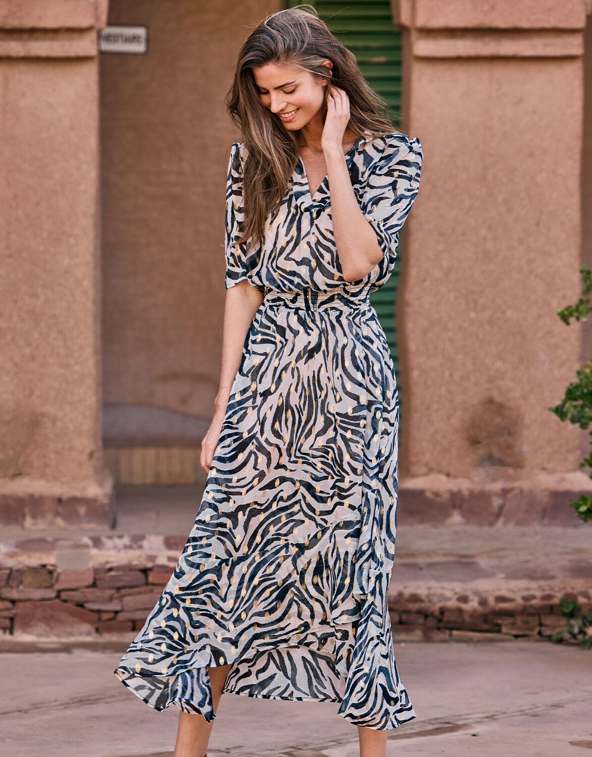 Model standing in the Perla Wild Stripes dress in chiffon with an animal print.
