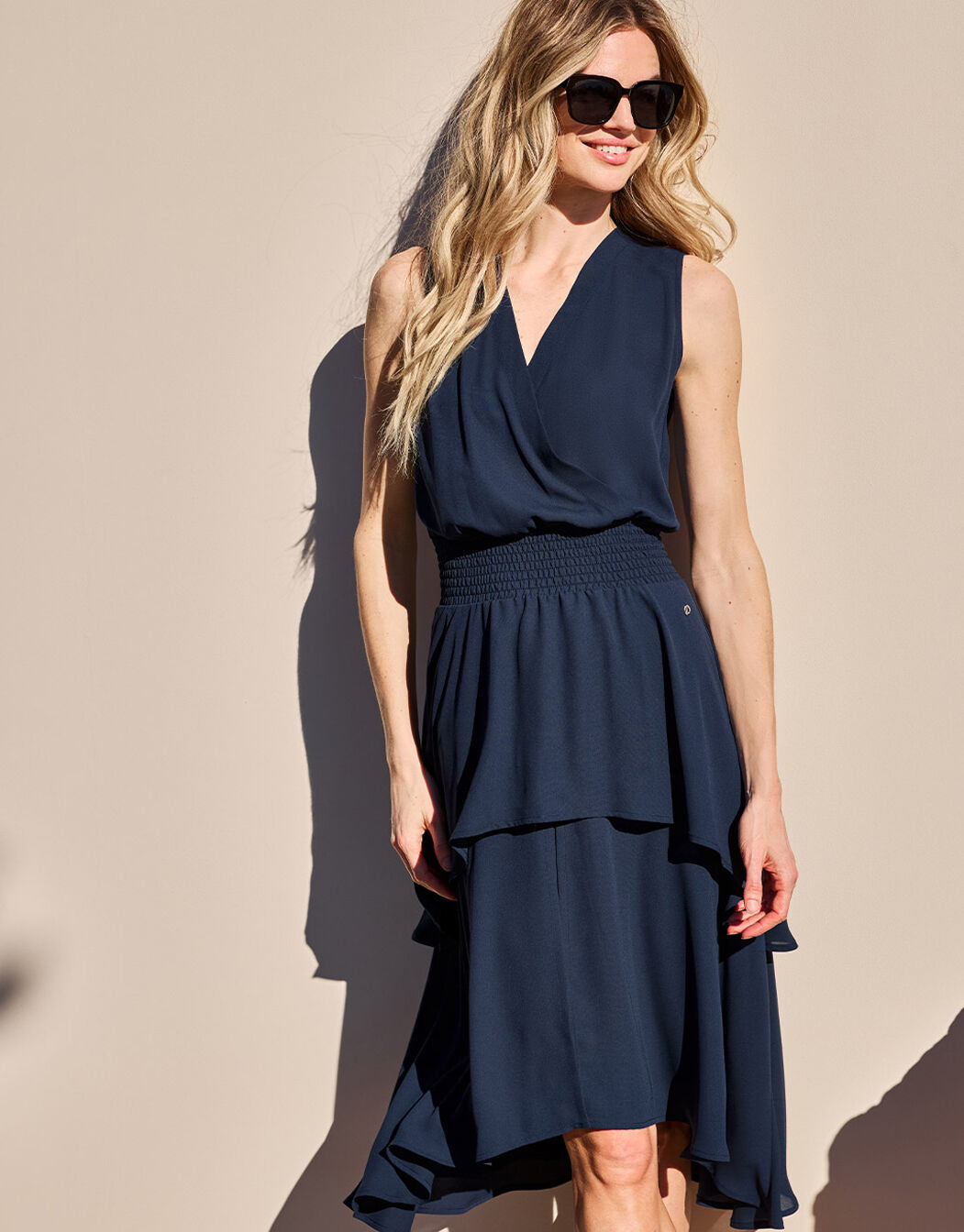 Model standing in the Tilly Midnight Blue dress in crepe georgette with a tiered skirt.