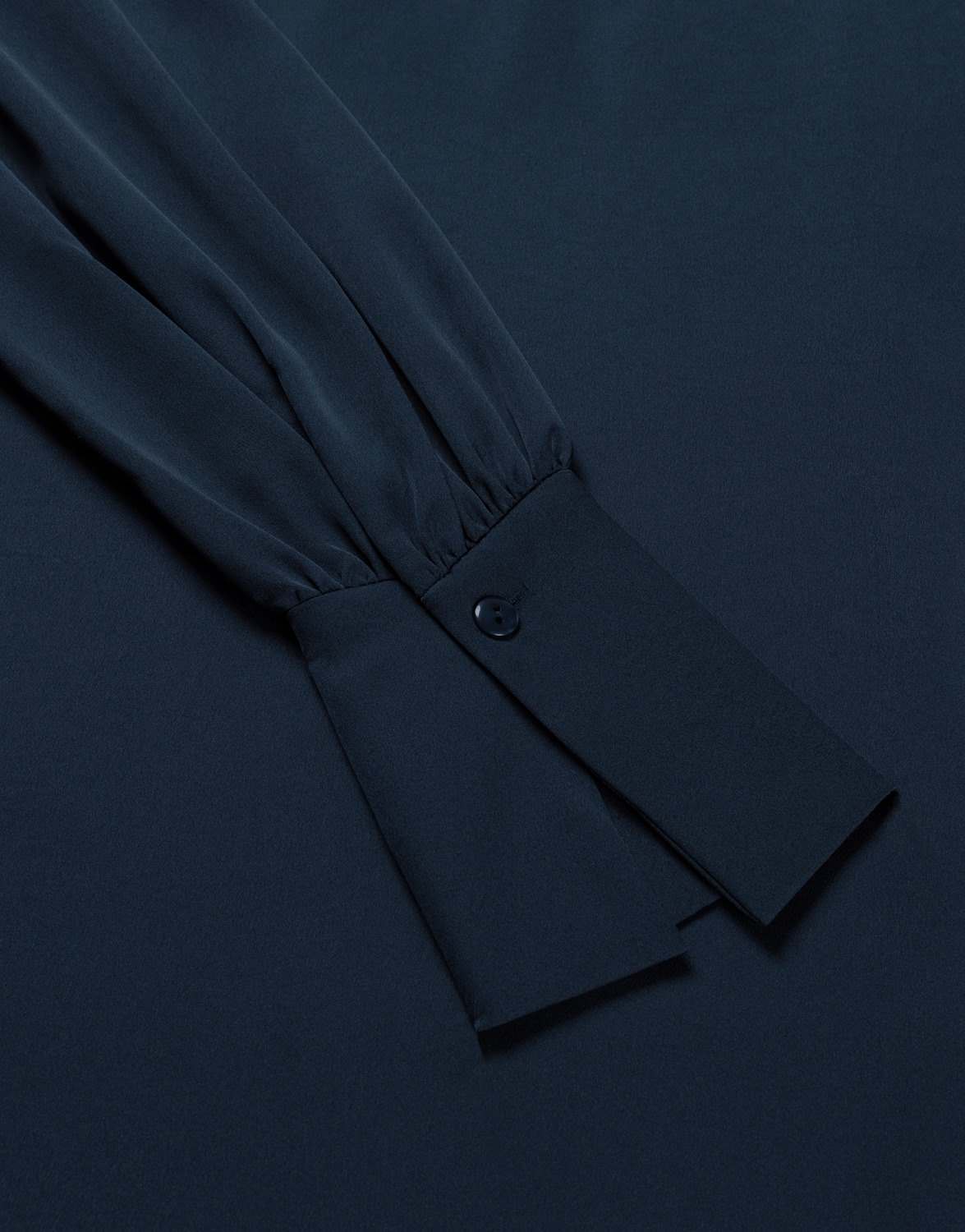 Detail of the Alix Midnight Blue satin blouse showing the buttoned cuff.