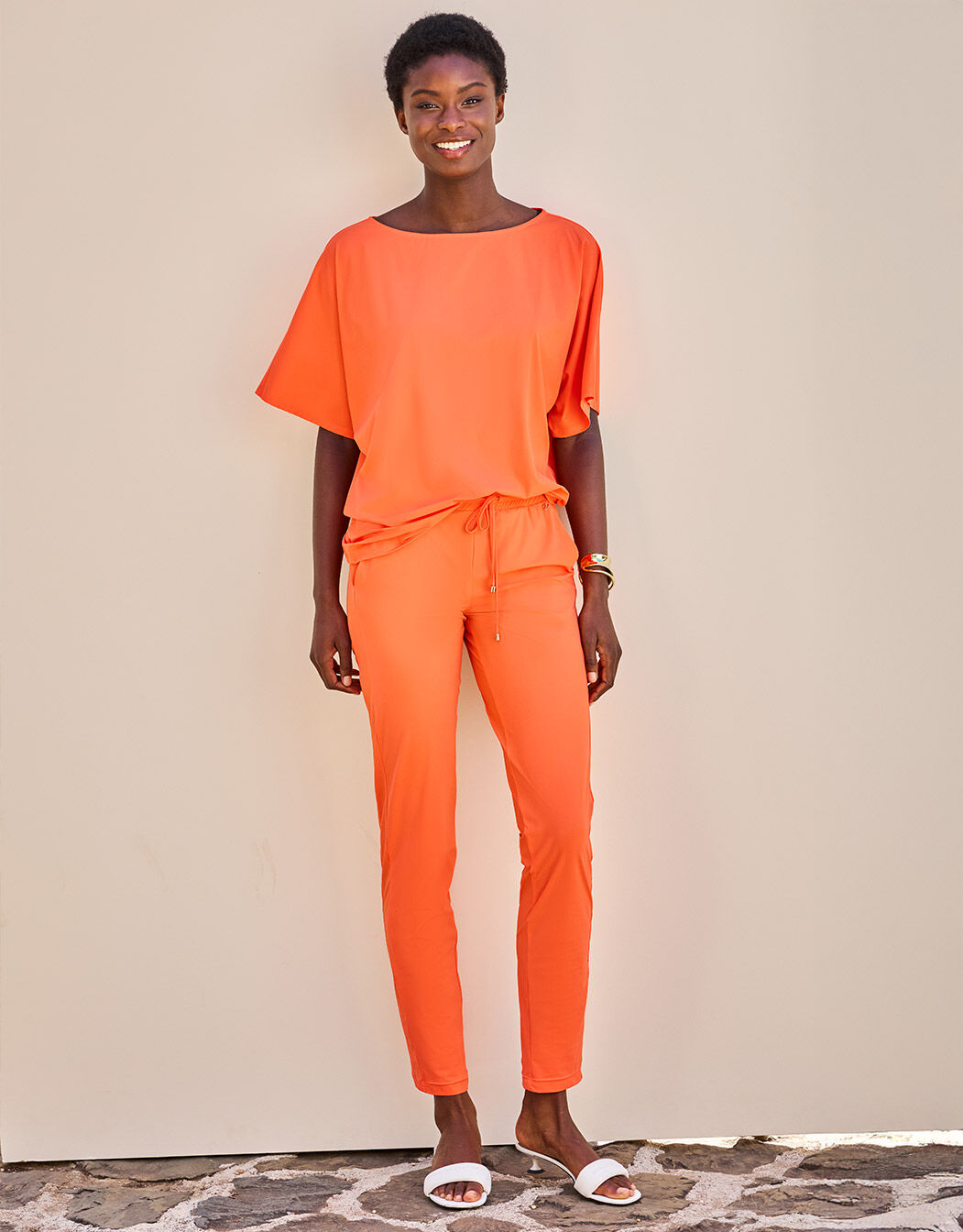 Model standing in the Valencia Soft Orange trousers in jersey lycra with a matching top.