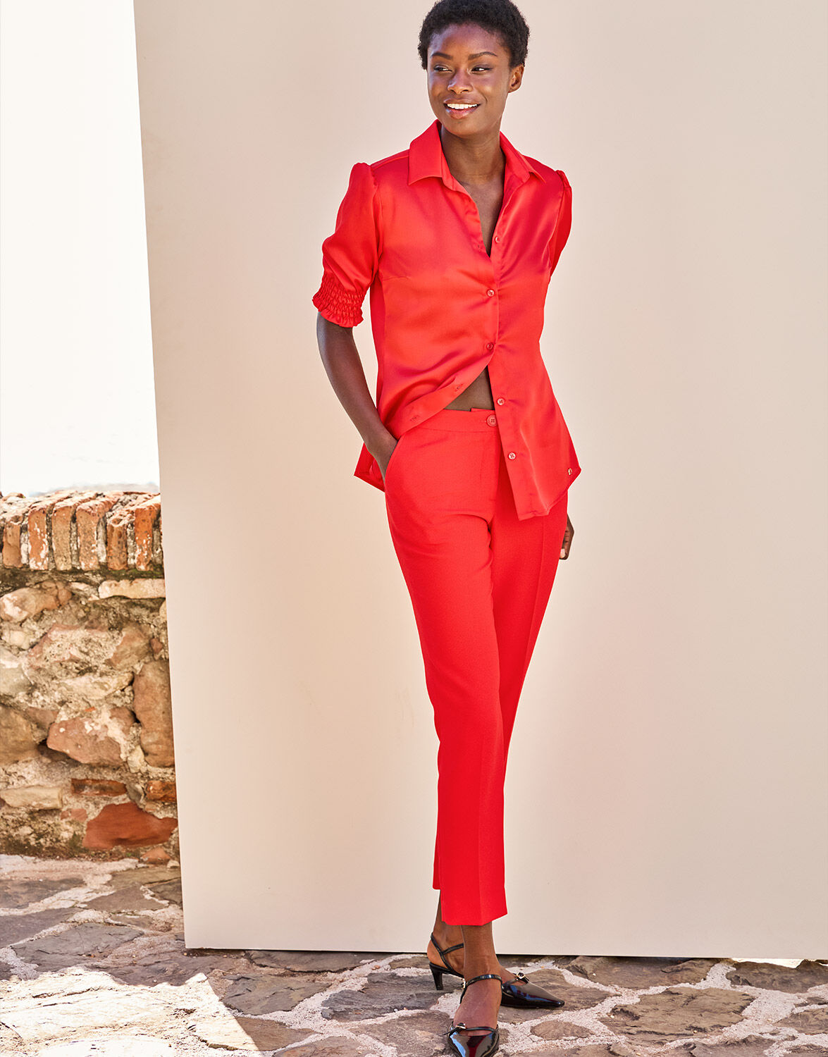 Model standing in the Seoul Hibiscus trousers in crepe satin with a matching blouse.