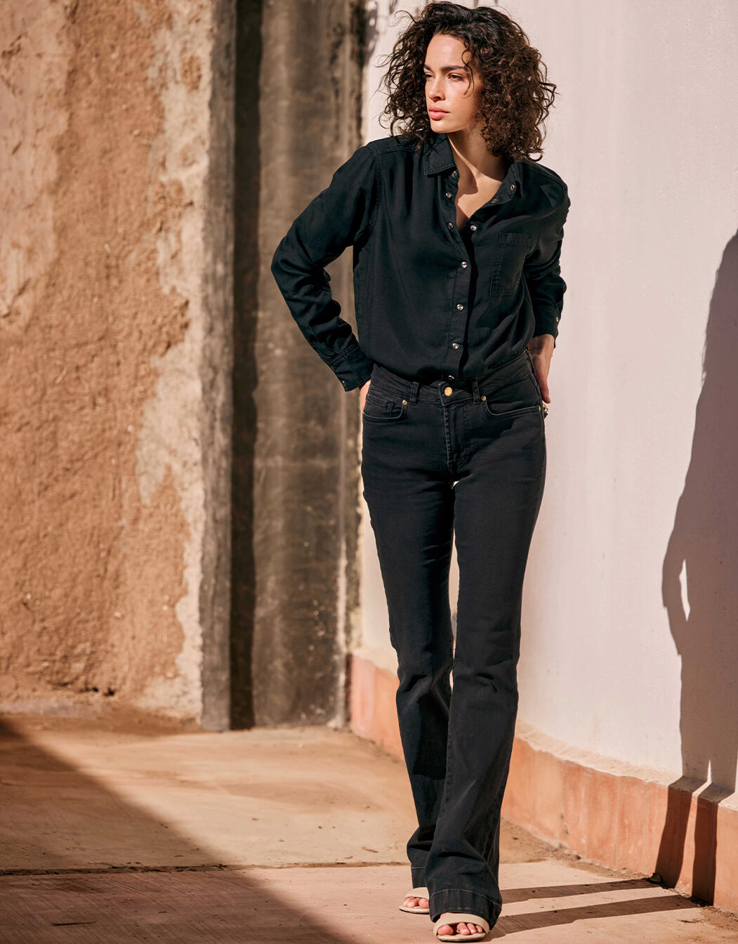 Model standing in the Madelin Washed Black jeans in stretch cotton with a black shirt.