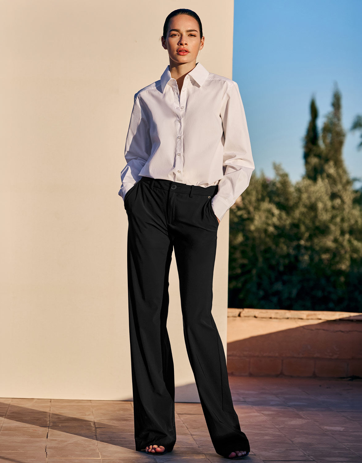 Model standing in the Lugano Black trousers in jersey lycra with a white shirt.