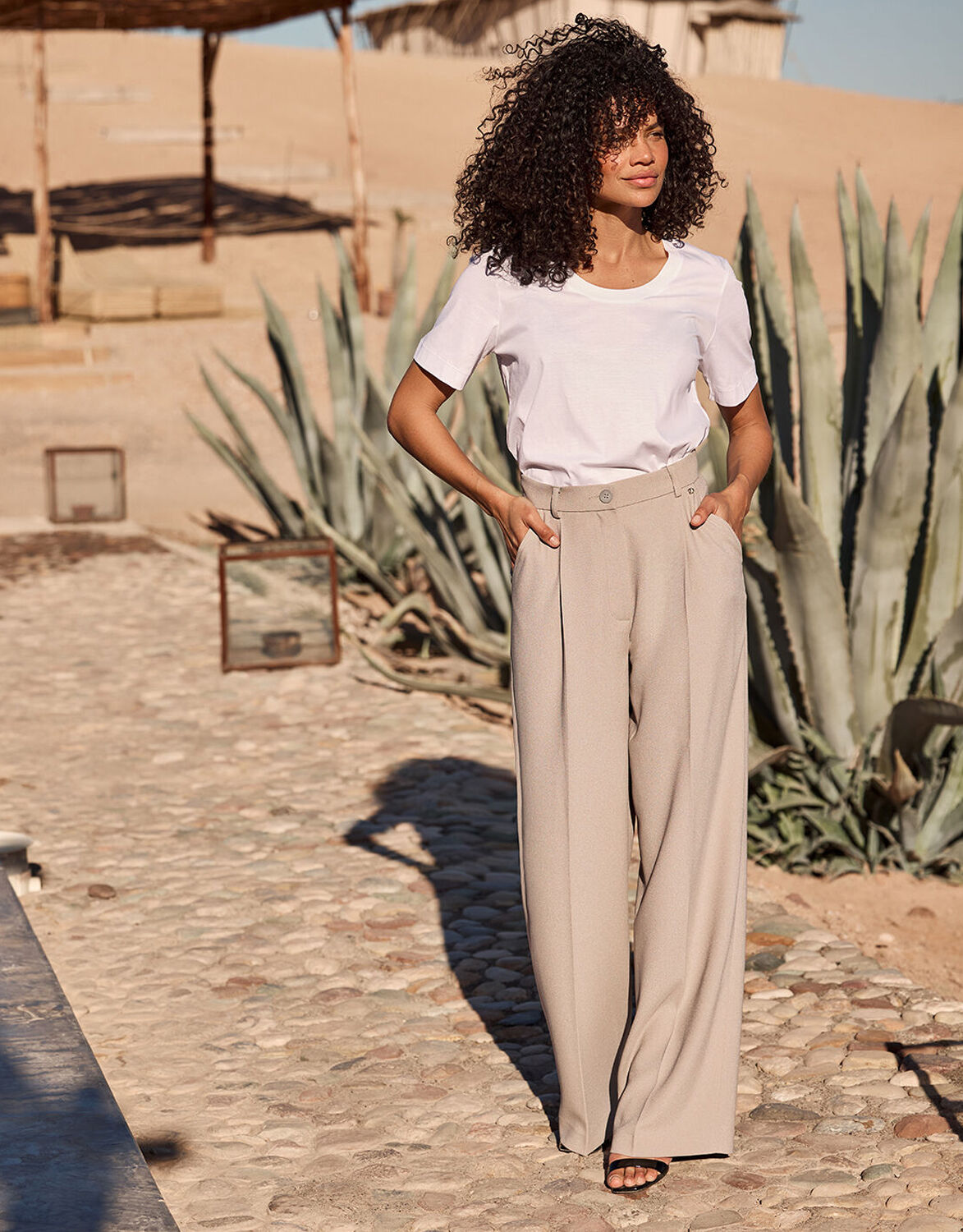 Model standing in the Torino Pebble trousers in crepe satin with a white T-shirt.