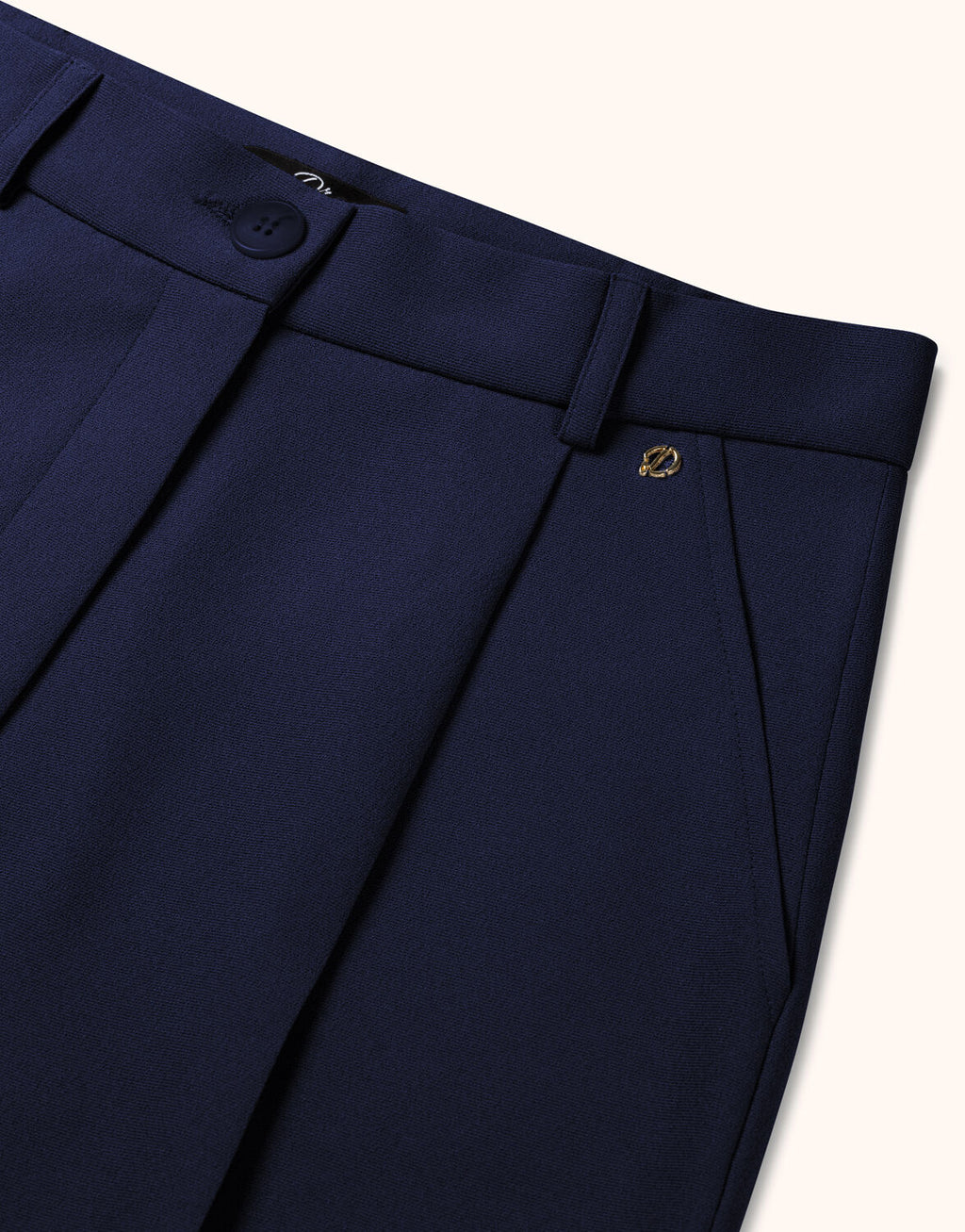 Dark blue wool trousers with a fine fabric texture and classic waistband, including an elegant gold emblem.