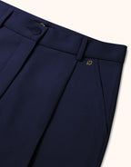 Dark blue wool trousers with a fine fabric texture and classic waistband, including an elegant gold emblem.