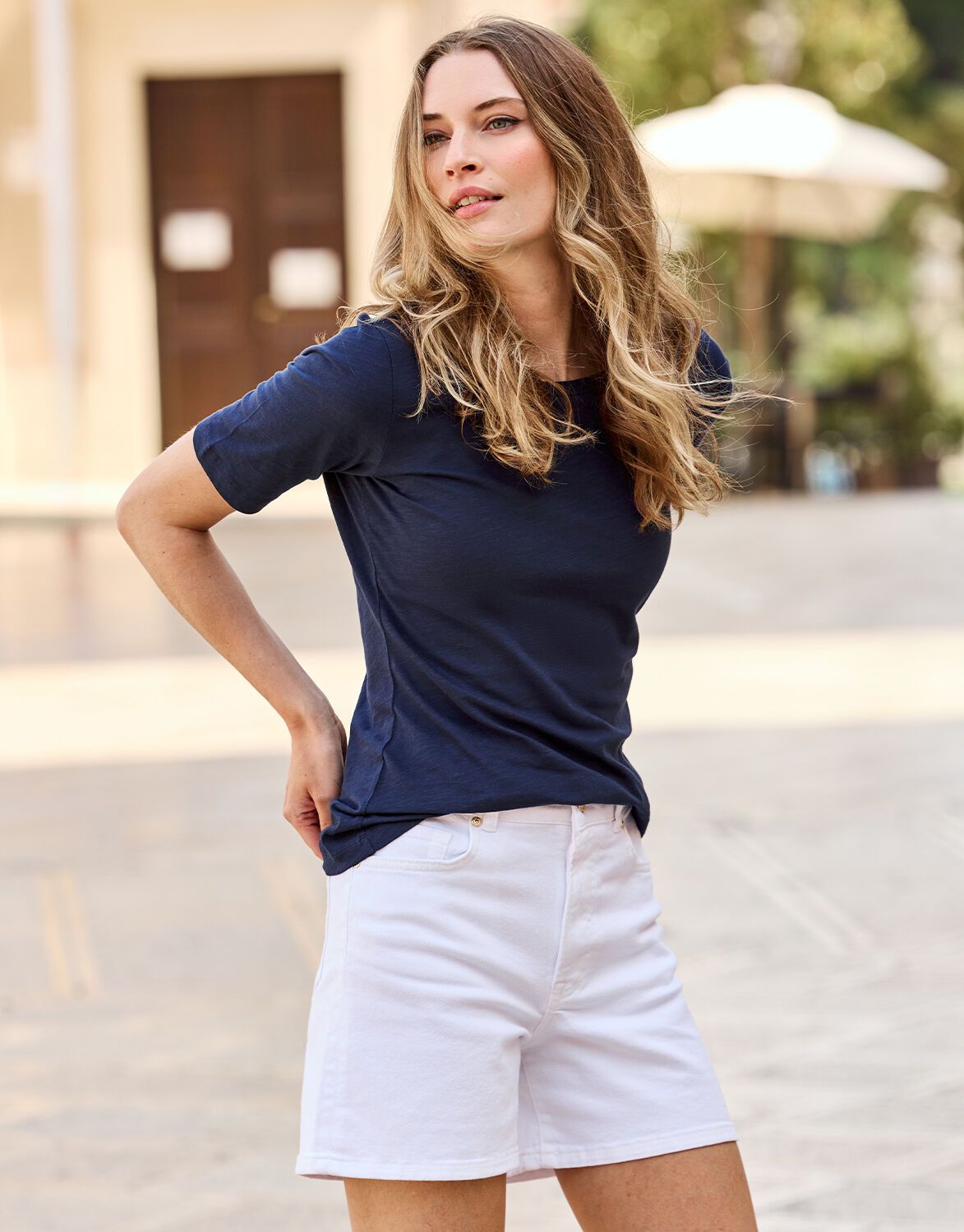 Model standing in the Como White shorts in stretch cotton, worn with a navy T-shirt.