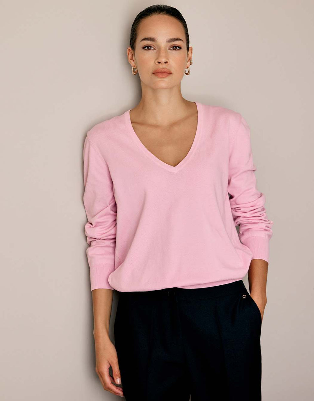 Model standing in the Loretta Pale Rose jumper in organic cotton knit with a V-neck.