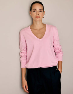 Model standing in the Loretta Pale Rose jumper in organic cotton knit with a V-neck.