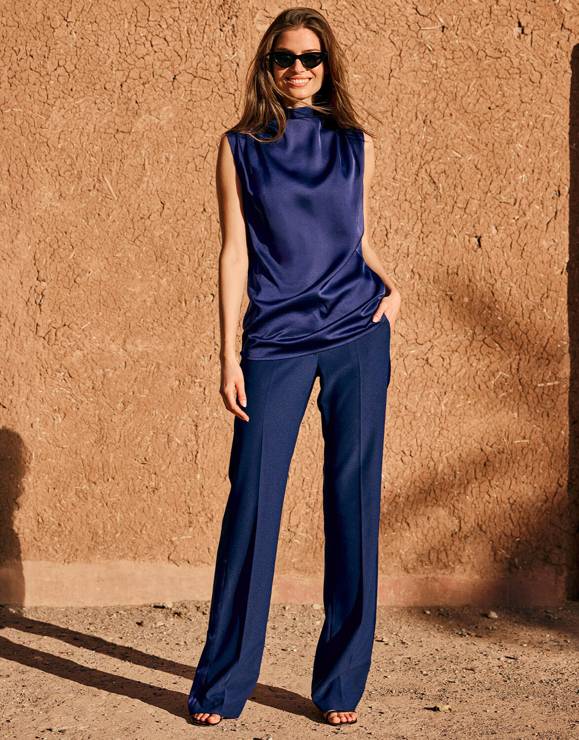 Model standing in the Geneva Sapphire Blue trousers in crepe satin with a satin top.
