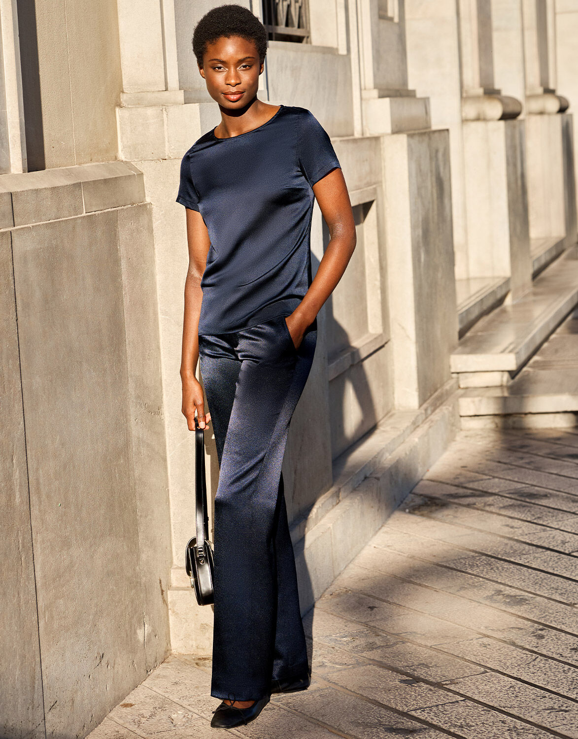 Model walking in the Geneva Midnight Blue Satin trousers in crepe satin with a satin top.