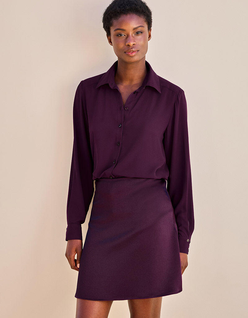 Model standing in the Gigi Deep Aubergine Satin skirt in crepe satin with a matching blouse.