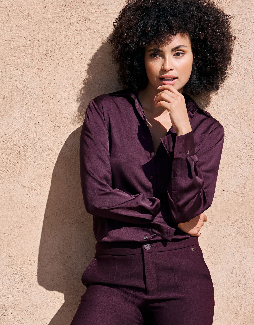 Model standing in the Estee Deep Aubergine blouse in satin with matching trousers.
