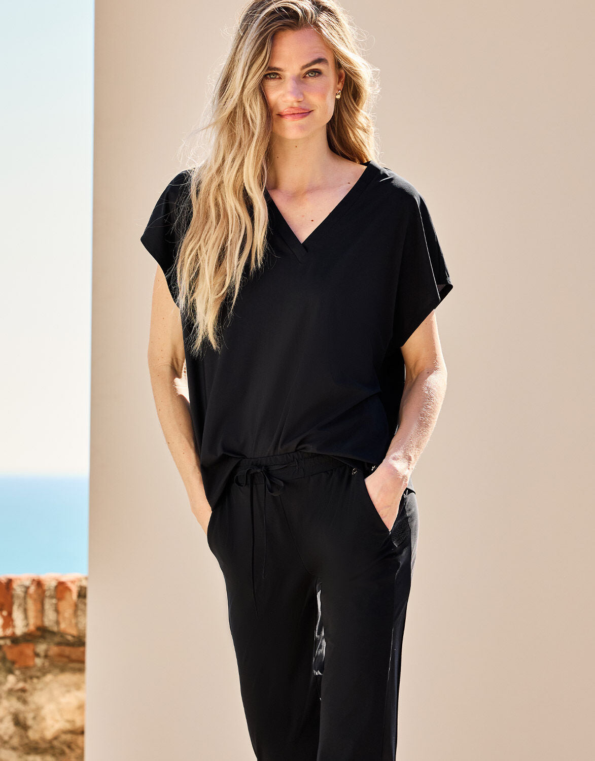 Model standing in the Liz Black top in jersey lycra with a V-neck and cap sleeves.