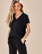 Woman poses in a casual black blouse and trousers.