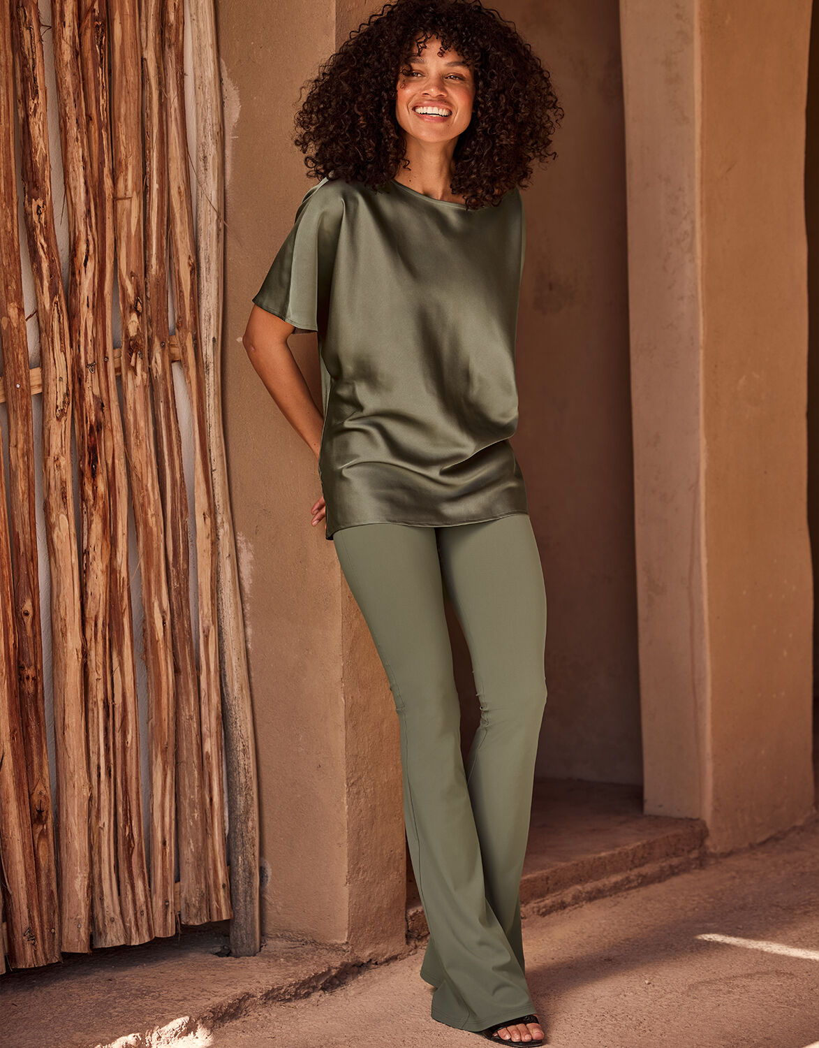 Model standing in the Jamie Olive top in satin with matching olive trousers.
