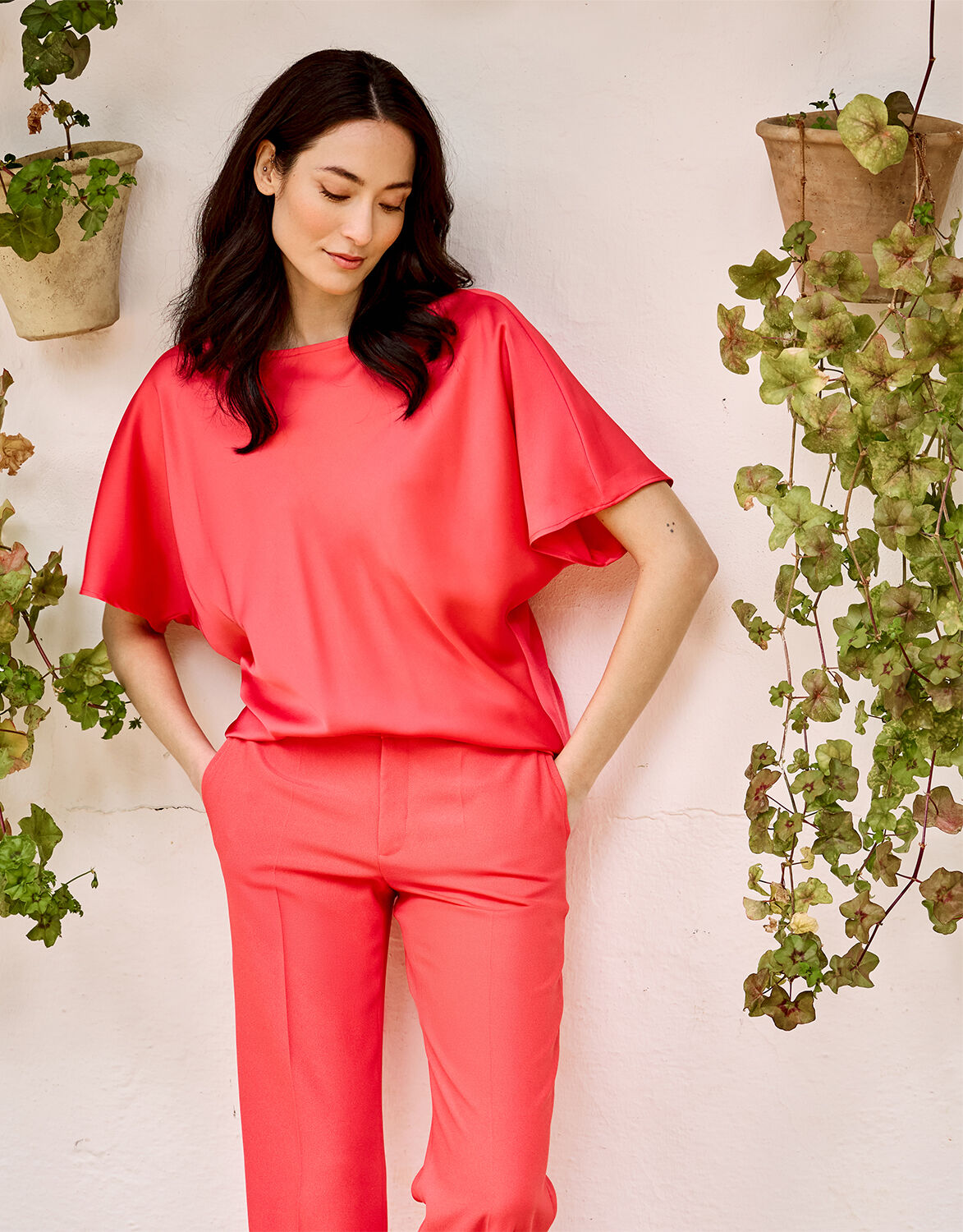 Model standing in the Jamie Coral top in satin with matching coral trousers.