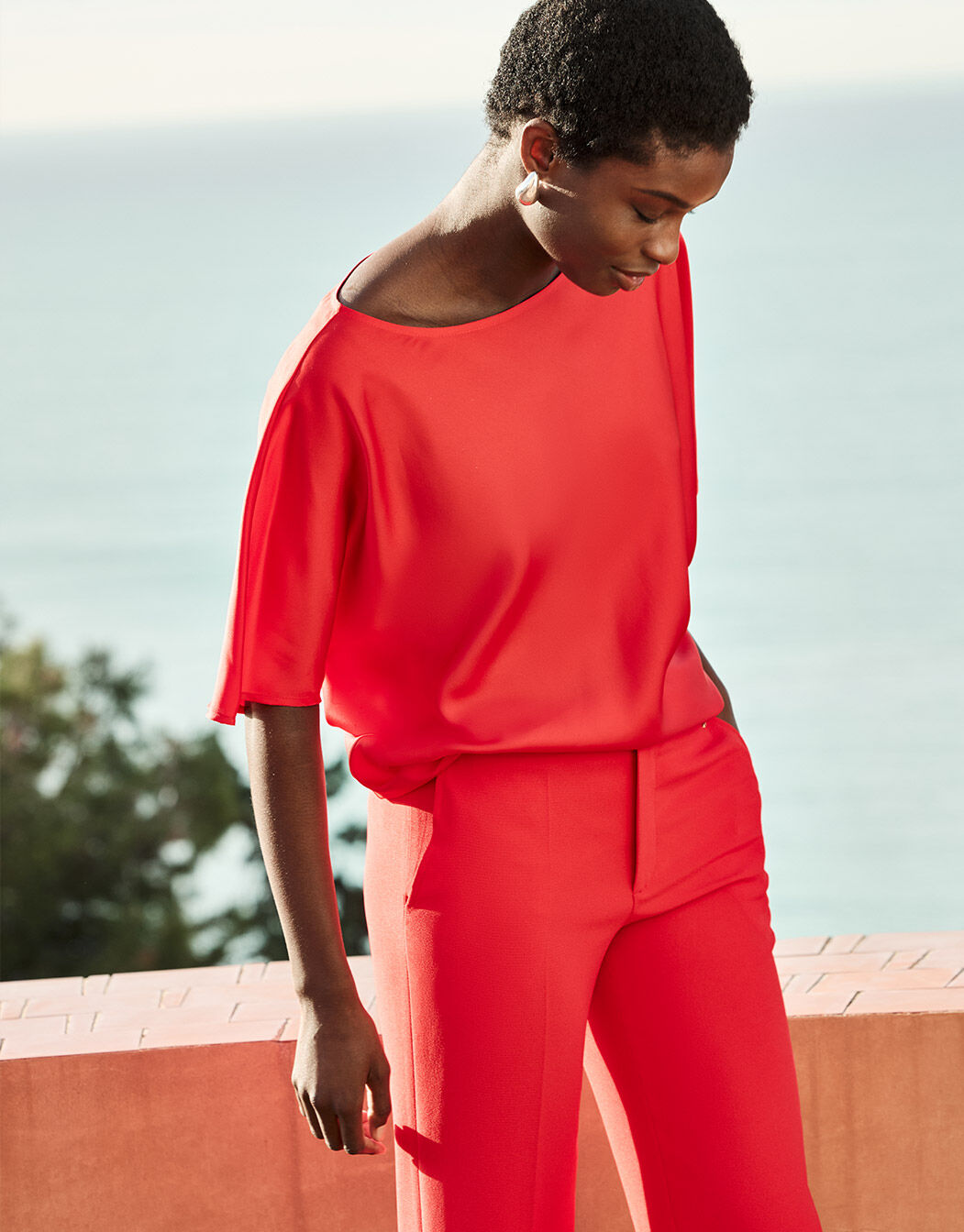 Model standing in the Jamie Hibiscus top in satin with matching red trousers.