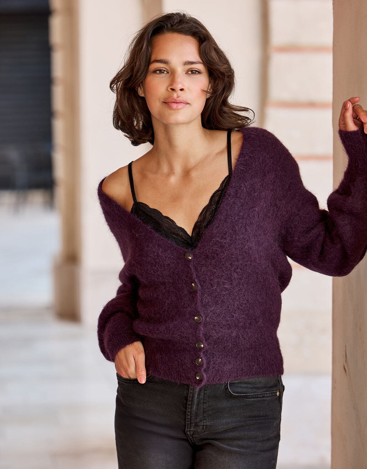 Model standing in the Leonora Deep Aubergine cardigan in alpaca blend with a V-neck.