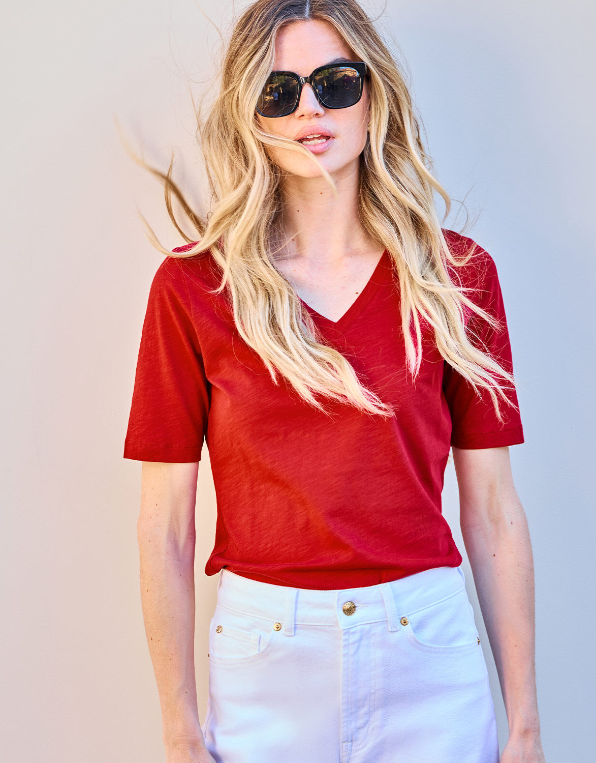 Model standing in the Chiara Raspberry Red T-shirt in cotton with white jeans.
