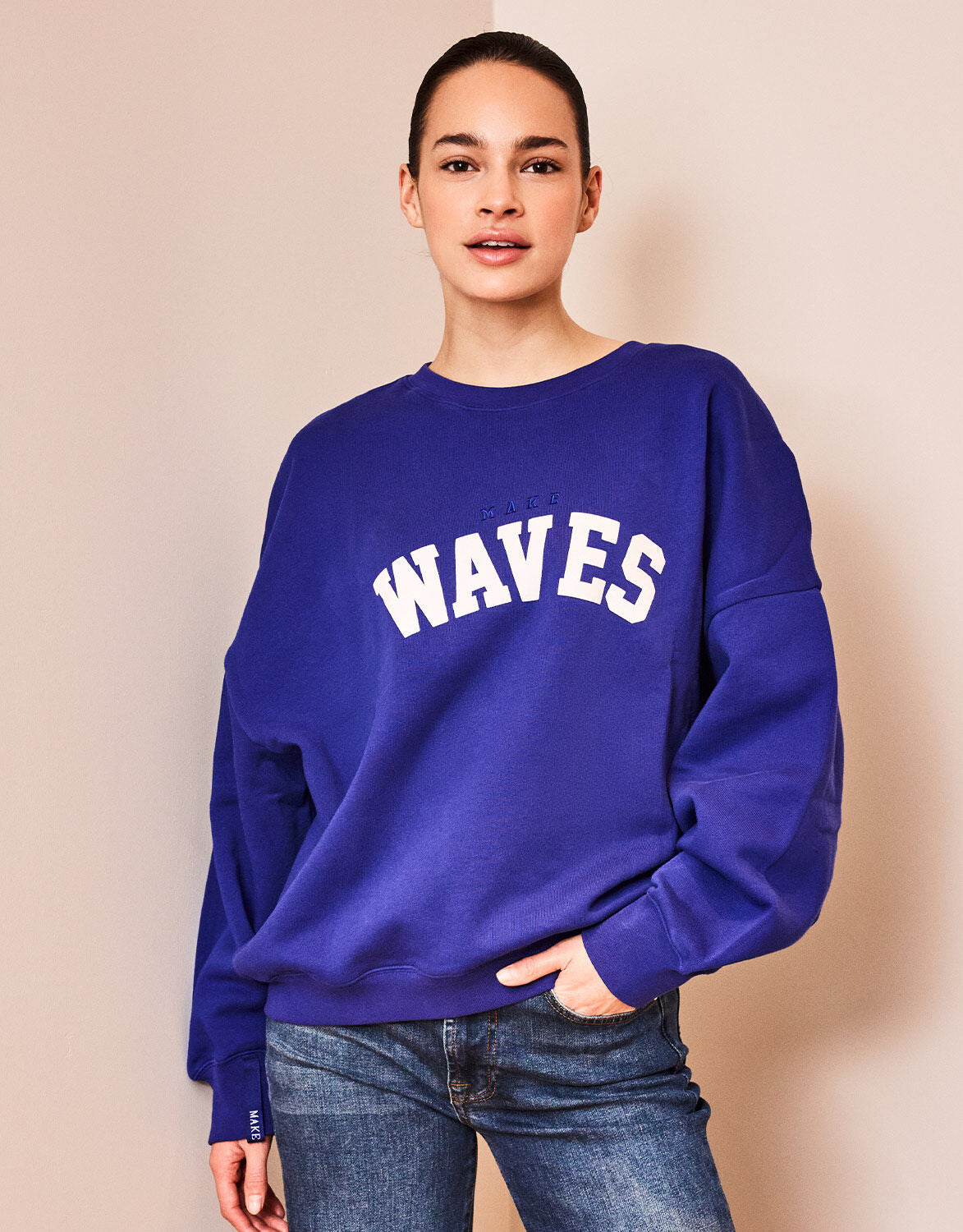 Model standing in the Story Sweater Marine Blue in organic cotton knit with a WAVES print.