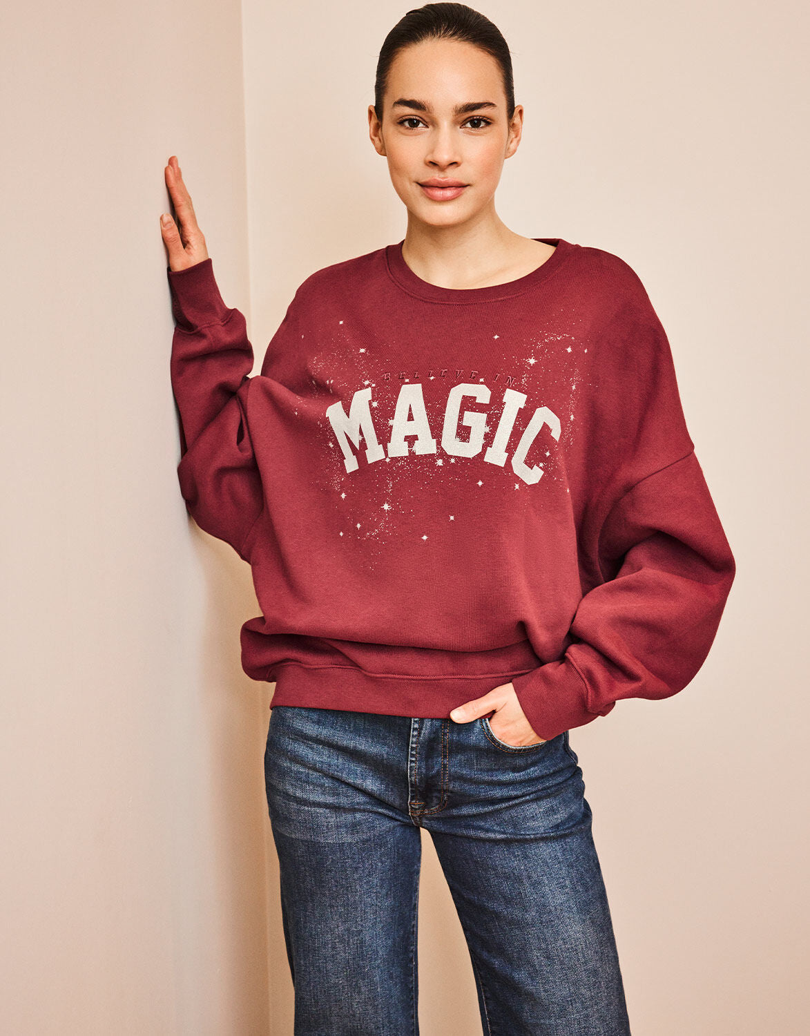 Model standing in the Story Sweater Ruby Red in organic cotton knit with a MAGIC print.