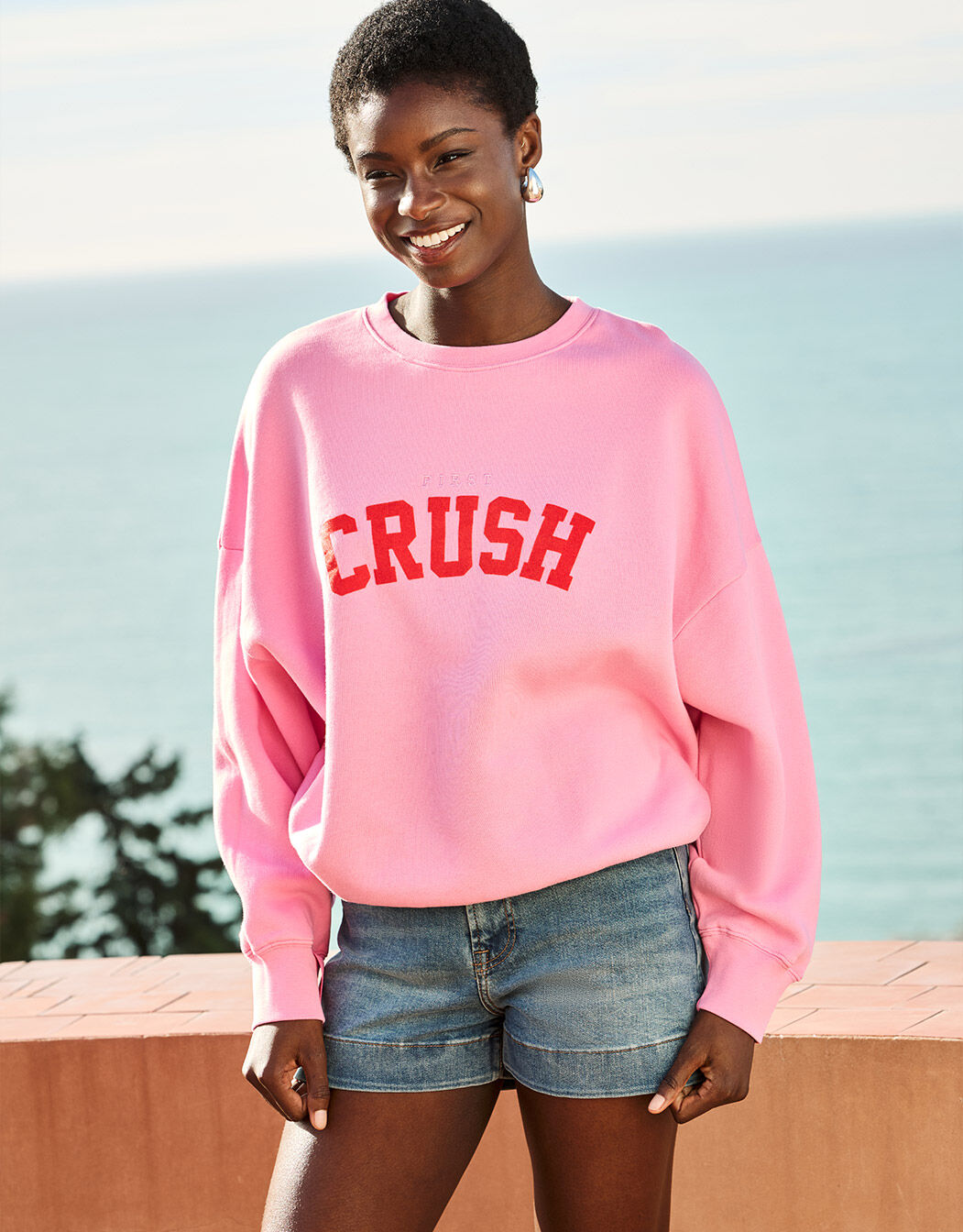 Model standing in the Story Sweater Candy in organic cotton knit with a CRUSH print.