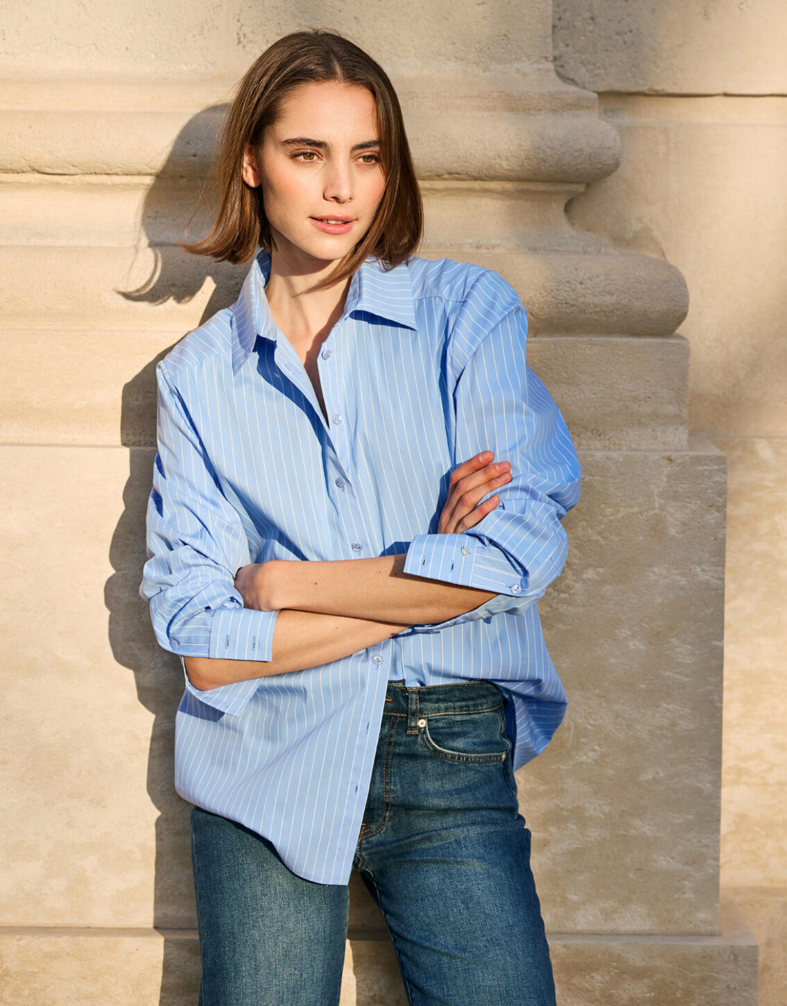 Model standing in the Naya Pin Stripe Light Blue blouse in cotton stretch poplin.