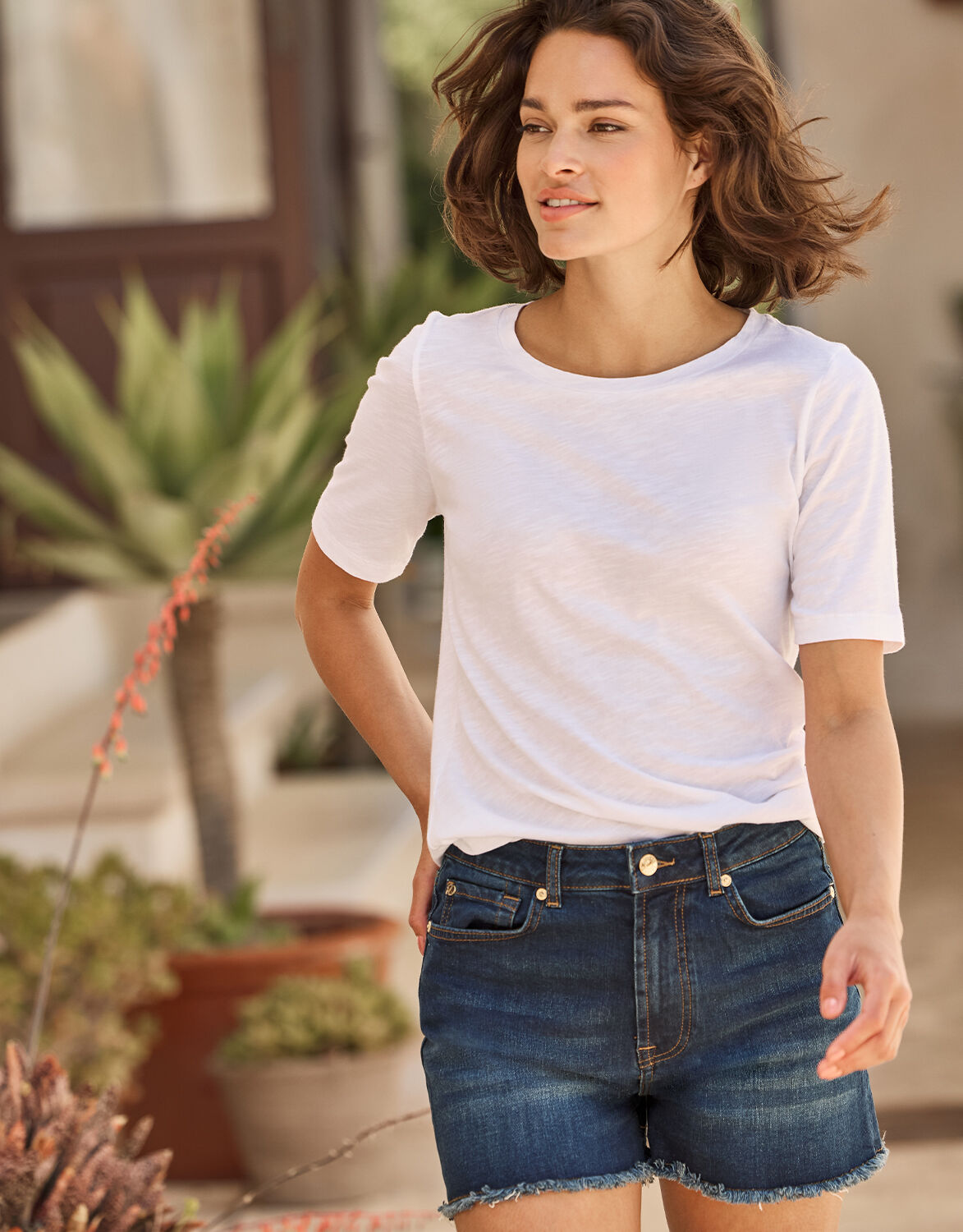 Model standing in the Lucca Dark Indigo shorts in stretch cotton with a white T-shirt.
