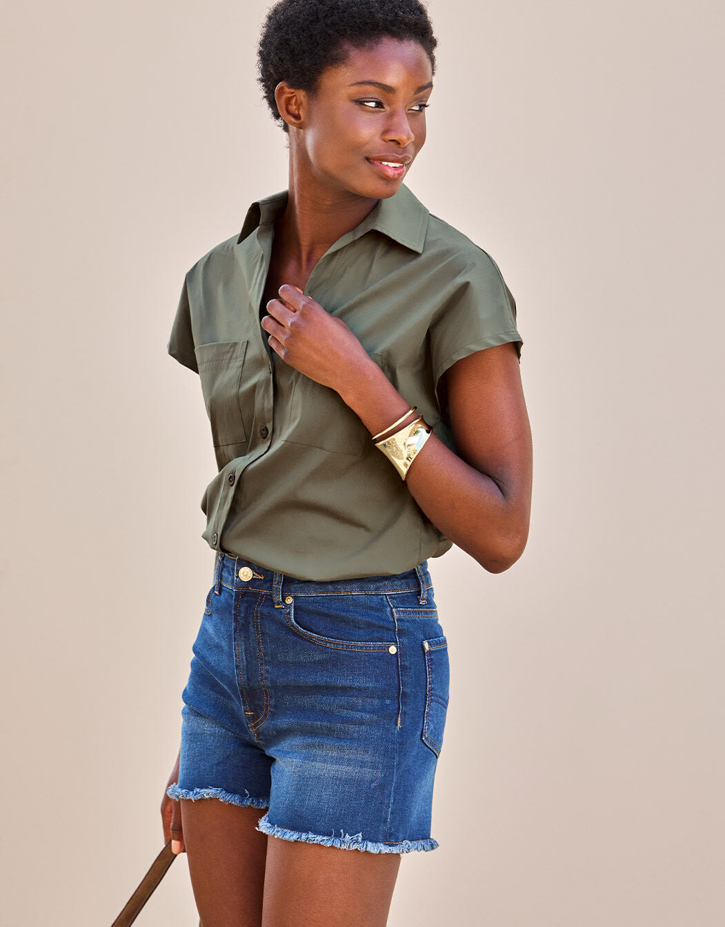 Olivgrüne Baumwollbluse mit kurzen Ärmeln und blaue Denim-Shorts, lässiger Sommermodestil.